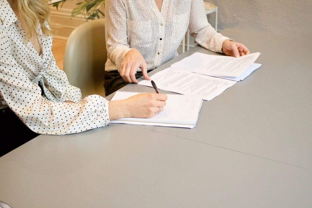 Everything about Condominiums. Two people are meeting and writing something down in a meeting minute.