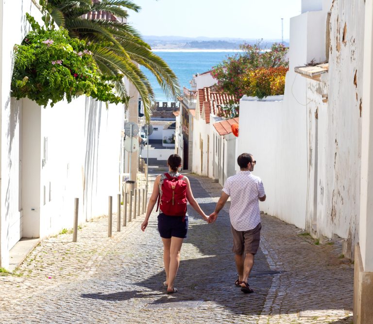 couple holding hands walking down the picturesque street of Lagos in Algarve, South of Portugal.