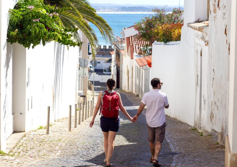 couple holding hands walking down the picturesque street of Lagos in Algarve, South of Portugal.