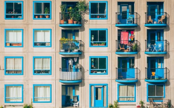 article cover image: Everything about Condominiums. In the picture, several windows and balconies are painted blue, with plants, chairs, and clothes.