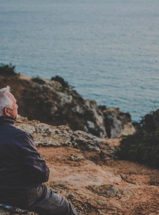 D7 visa in Portugal - Everything you need to know. The picture shows an elderly couple sitting on one of the cliffs on the coast of Lagos, Algarve.
