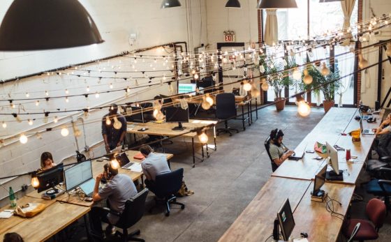 Digital Nomad Visa - Algarve. The image shows several people in a coworking space working at wooden tables with laptops.