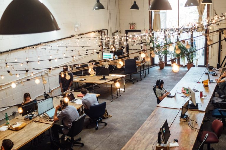 Digital Nomad Visa - Algarve. The image shows several people in a coworking space working at wooden tables with laptops.